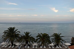A seaside view with palm trees and lounge chairs along the water's edge. - Paradise Beach Hotel (Zakynthos)