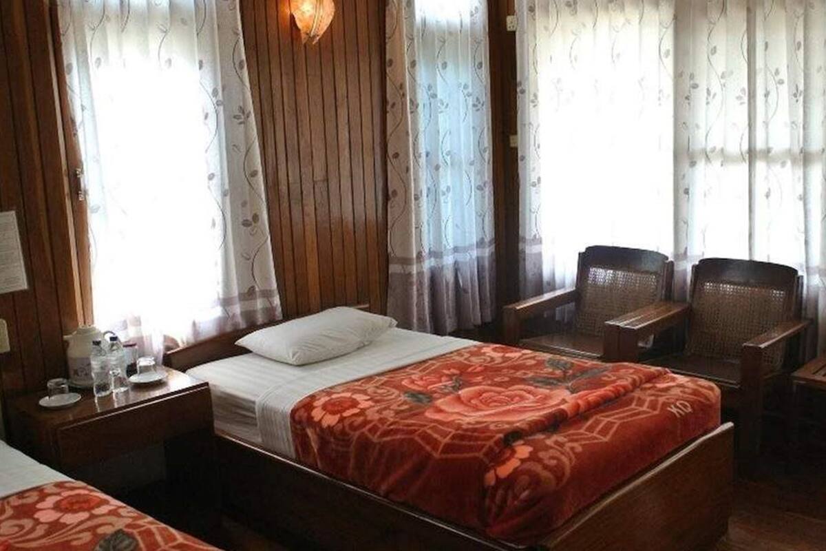 Ein Hotelzimmer mit einem Bett, zwei Stühlen, einem kleinen Tisch und einer Bank.