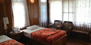 A hotel room with a bed, two chairs, a small table, and a bench. - Nanda Wunn Hotel - Hostel (Nyaungshwe)