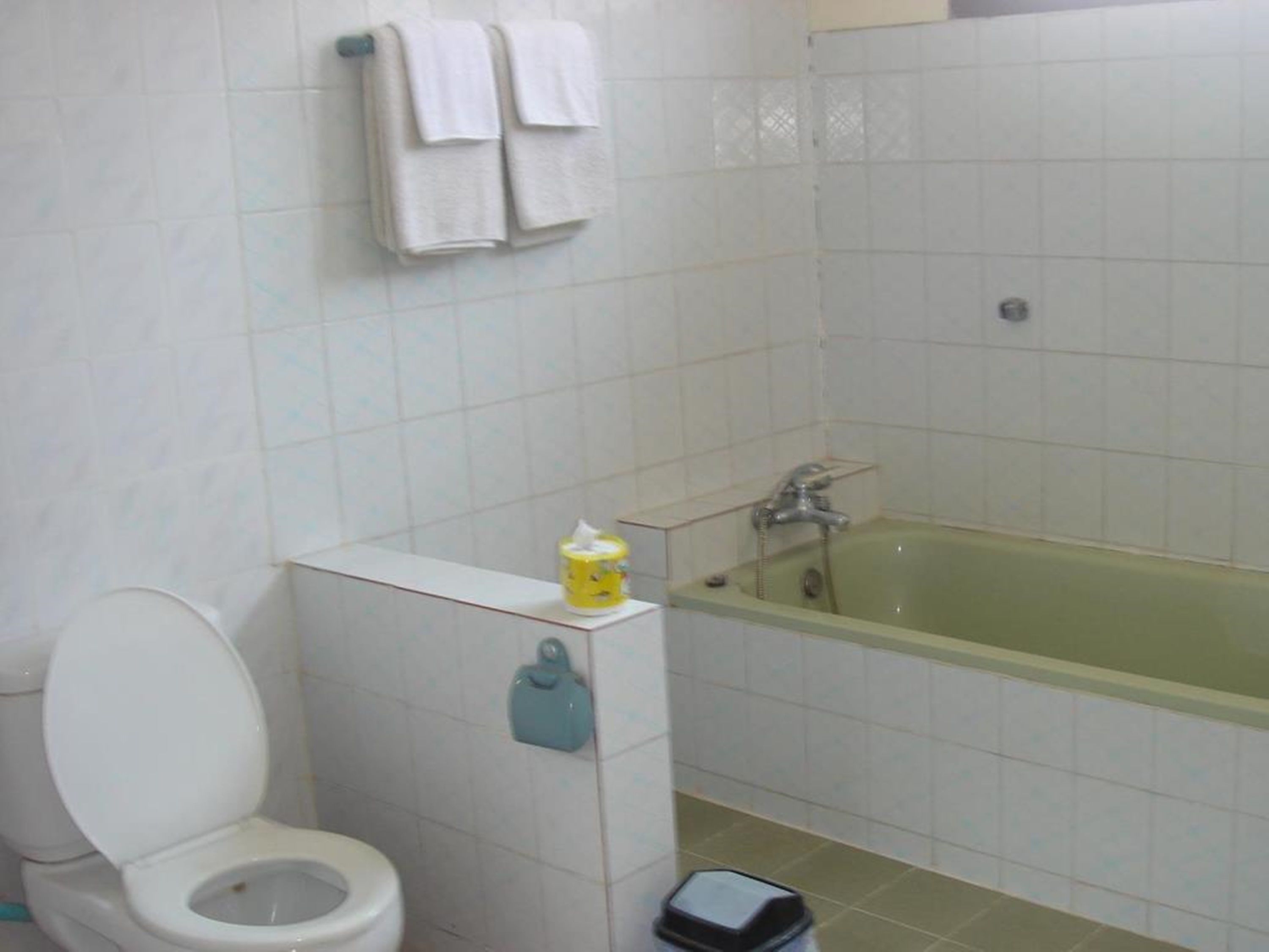 A bathroom with a toilet, a bathtub, and a towel rack with towels.