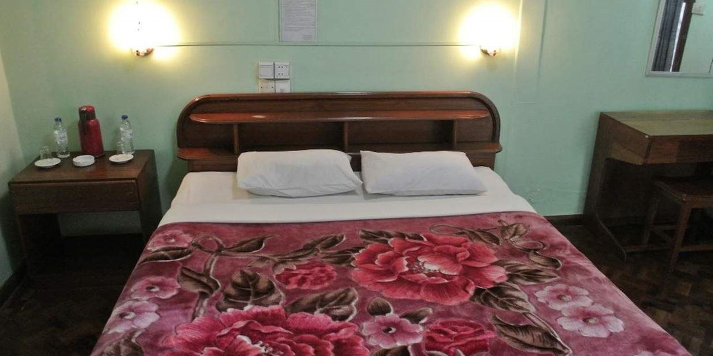 Una habitación con una cama, dos mesitas de noche, un escritorio y una silla.