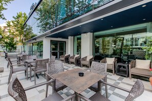 An outdoor patio with wicker furniture and a checkered floor. - Hotel Verona (Cesenatico)