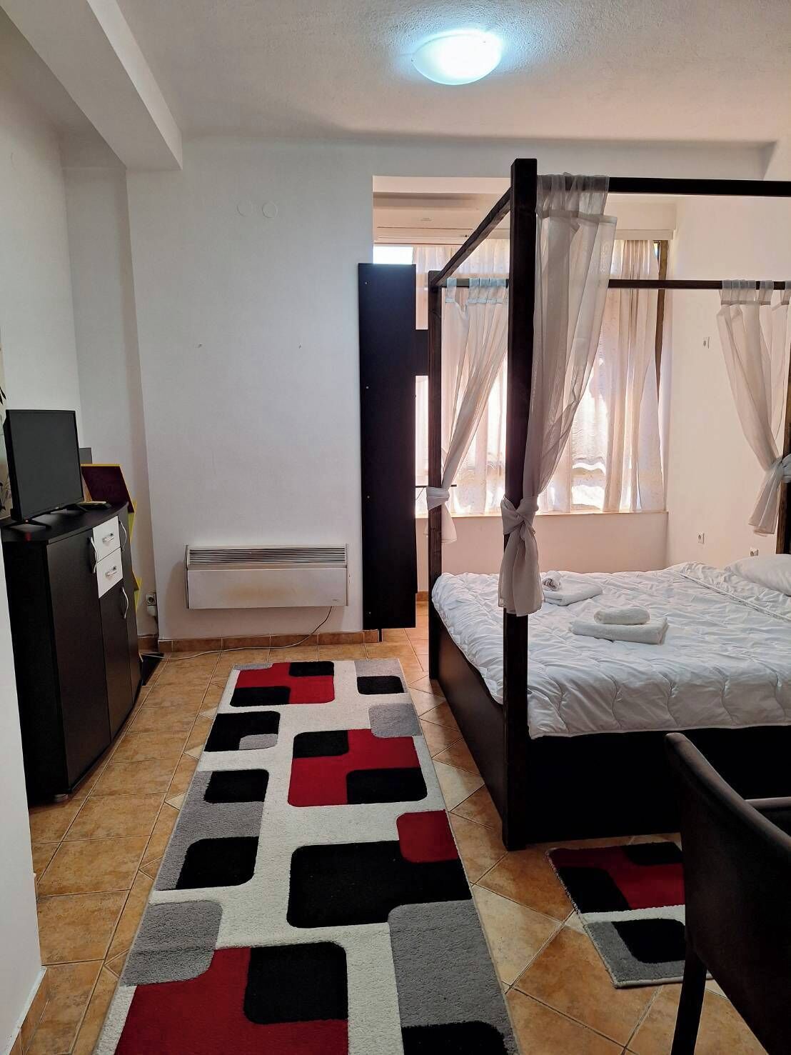 A bedroom with a four-poster bed, a desk with a computer, and a radiator.