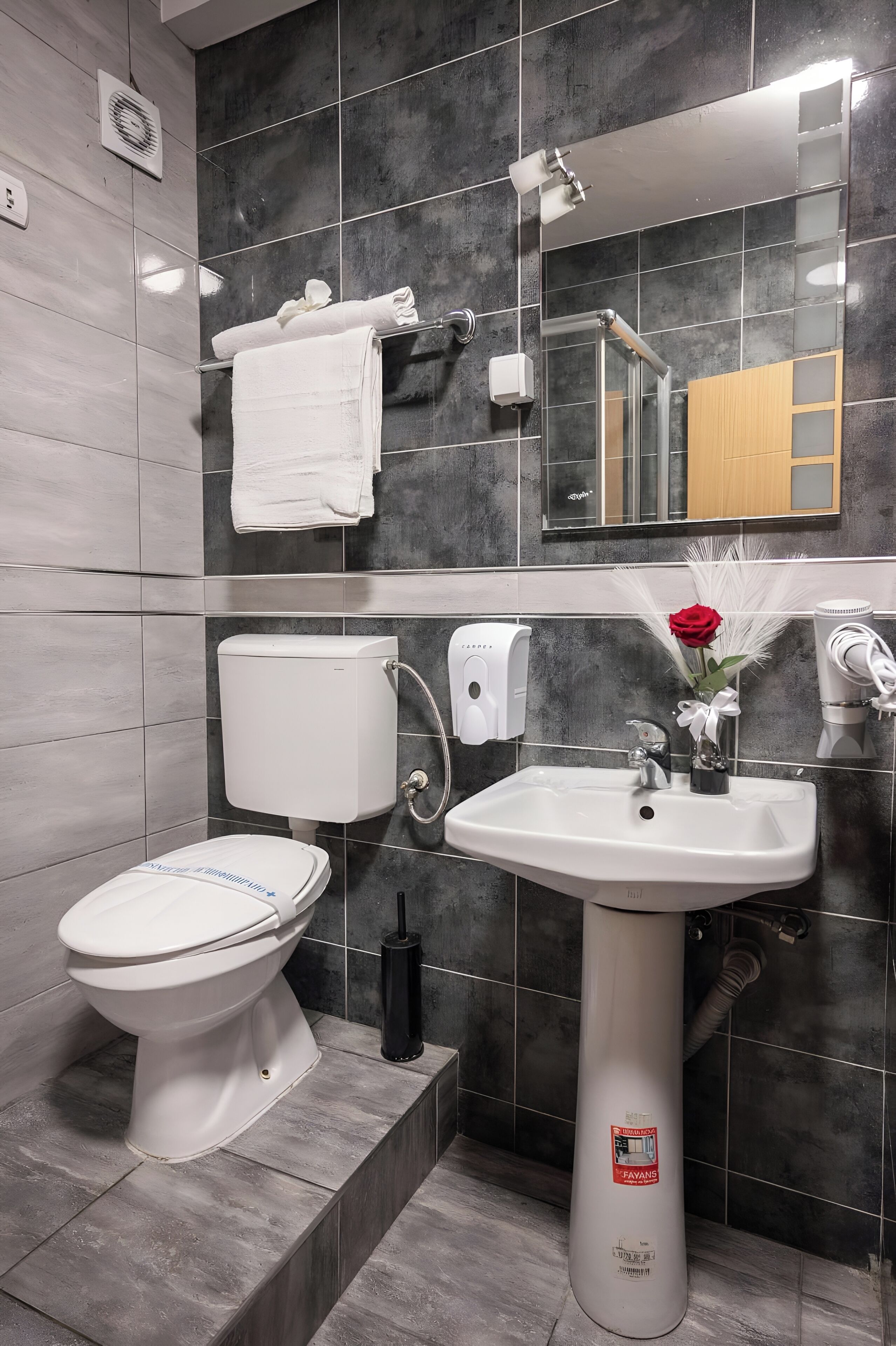 Een moderne badkamer met toilet, wastafel en handdoekhouder.