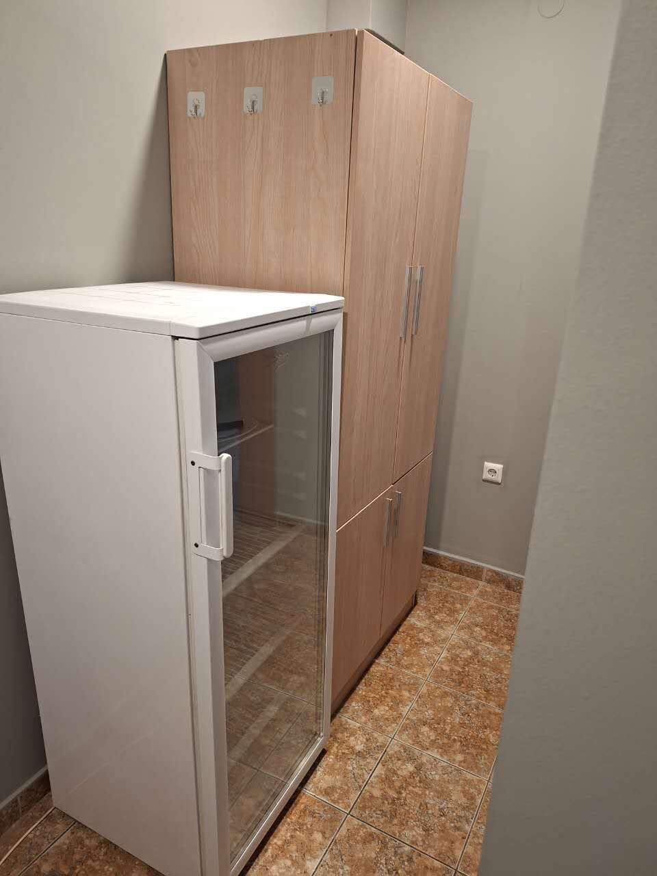 A compact kitchenette with a white refrigerator, a glass door freezer, and wooden cabinets.