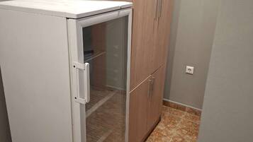 A compact kitchenette with a white refrigerator, a glass door freezer, and wooden cabinets.