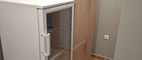 A compact kitchenette with a white refrigerator, a glass door freezer, and wooden cabinets.