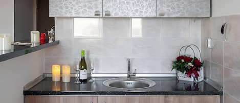 A modern kitchen with a marble backsplash, wooden cabinets, and a black countertop.