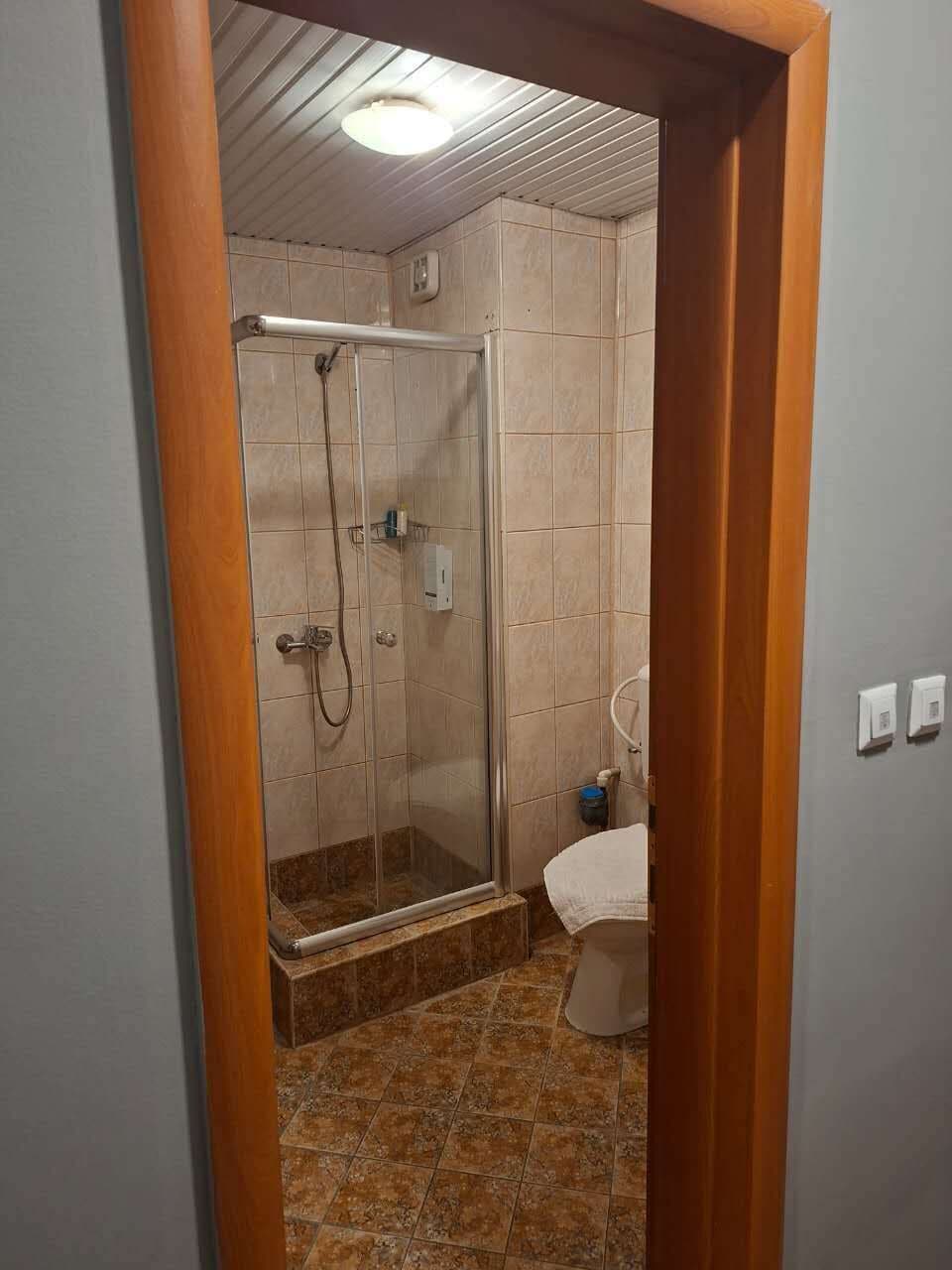 A bathroom with a shower, toilet, and a tiled floor.