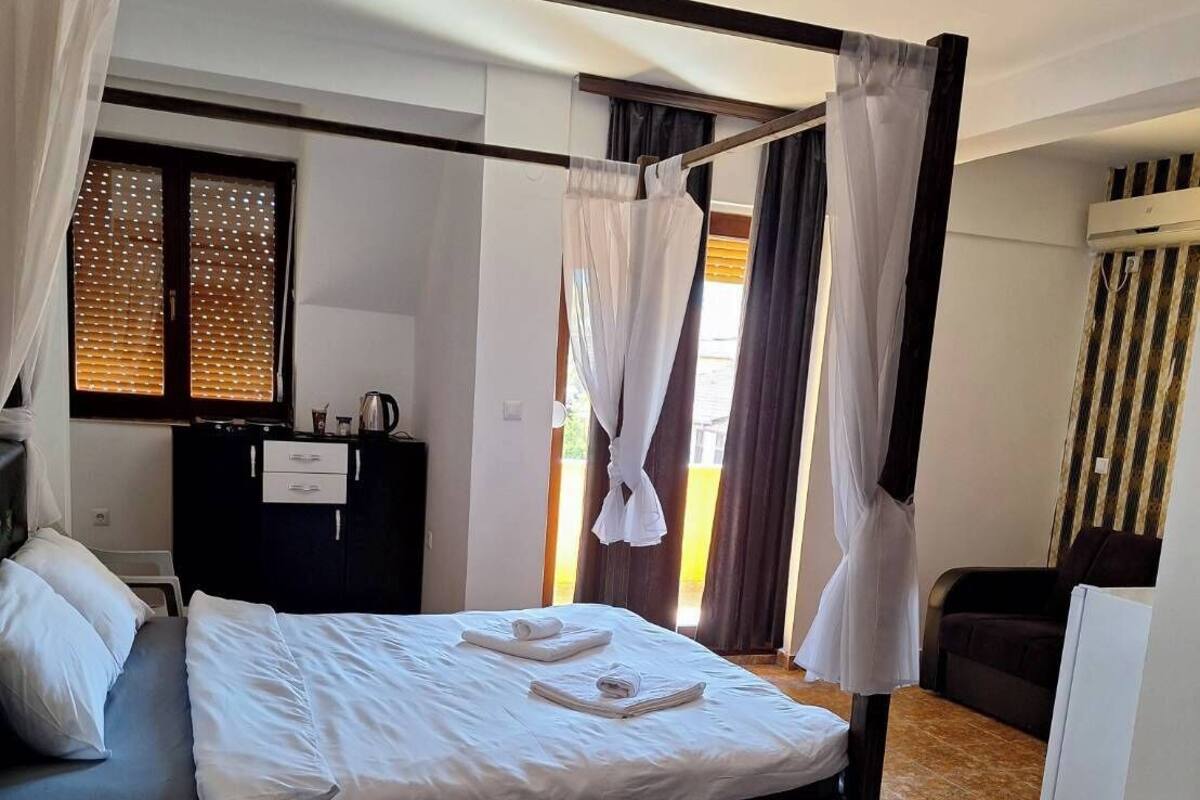 Une chambre moderne avec un lit à baldaquin, un bureau avec une chaise, une petite table et un tapis à motifs.
