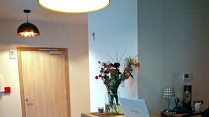 Una reception con una scrivania portatile, un vaso di fiori e una lampada da tavolo.