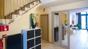 Un intérieur spacieux avec un escalier menant à un niveau supérieur, un extincteur, un petit placard et une porte donnant sur une autre pièce.