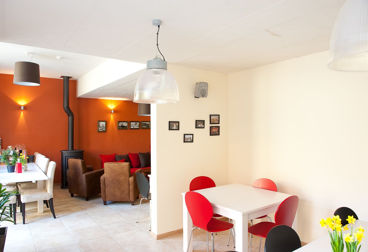 Un salon moderne avec un coin repas, comprenant une cheminée, des meubles rouges et blancs, et des œuvres d’art accrochées au mur.