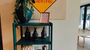 Un comptoir d’accueil avec une enseigne indiquant « Lesiven City Hostel », une plante en pot et une étagère contenant divers objets, notamment un crâne, des livres et des lanternes.