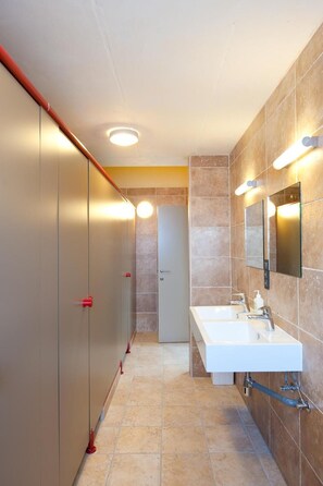 A modern bathroom with two sinks, a mirror, and a door. - Leuven City Hostel (Leuven)