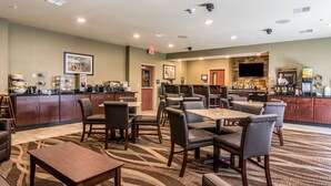Een hotel lobby met een bar, zithoeken en een keuken op de achtergrond.