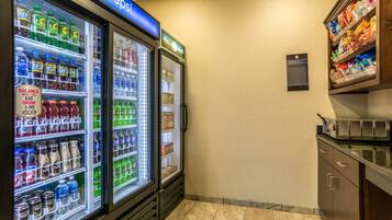 A hotel kitchenette with a refrigerator stocked with beverages and a microwave.