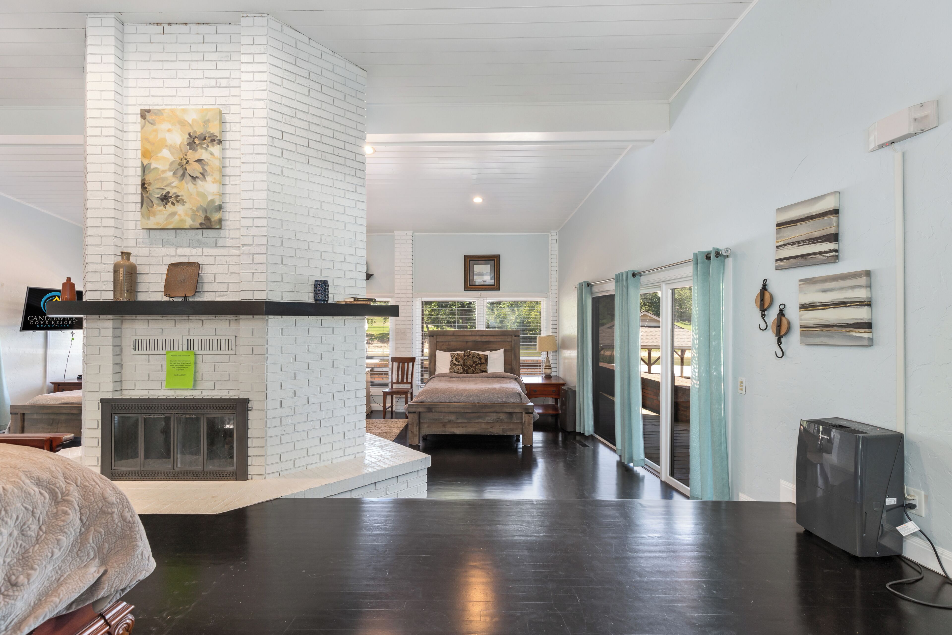 A spacious room with a fireplace, a bed, a television, and a view of the outdoors.