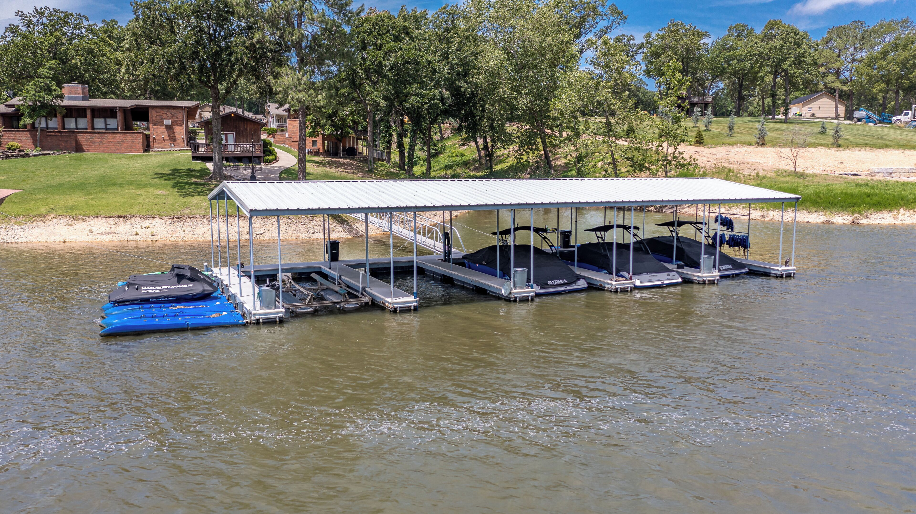 A lakeside dock with several boats and a covered seating area.