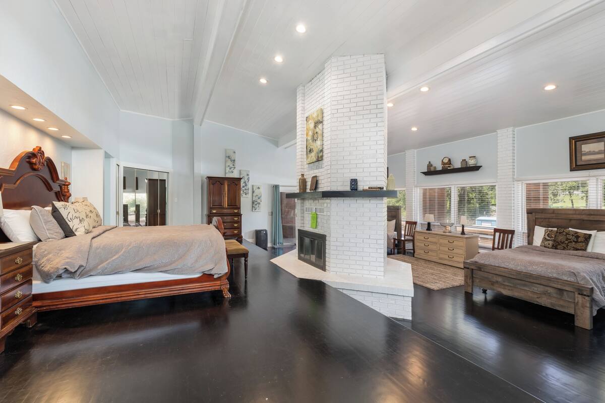 A spacious bedroom with a large bed, a fireplace, and a dining area with a view.