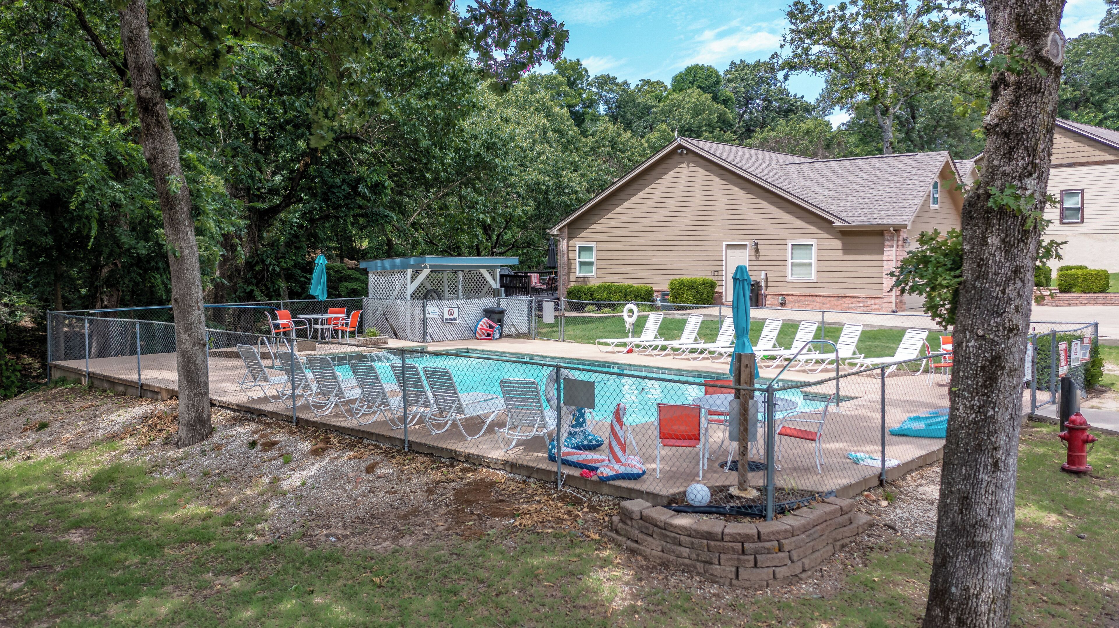 Un jardin avec une piscine, des chaises longues et un espace salon abrité.