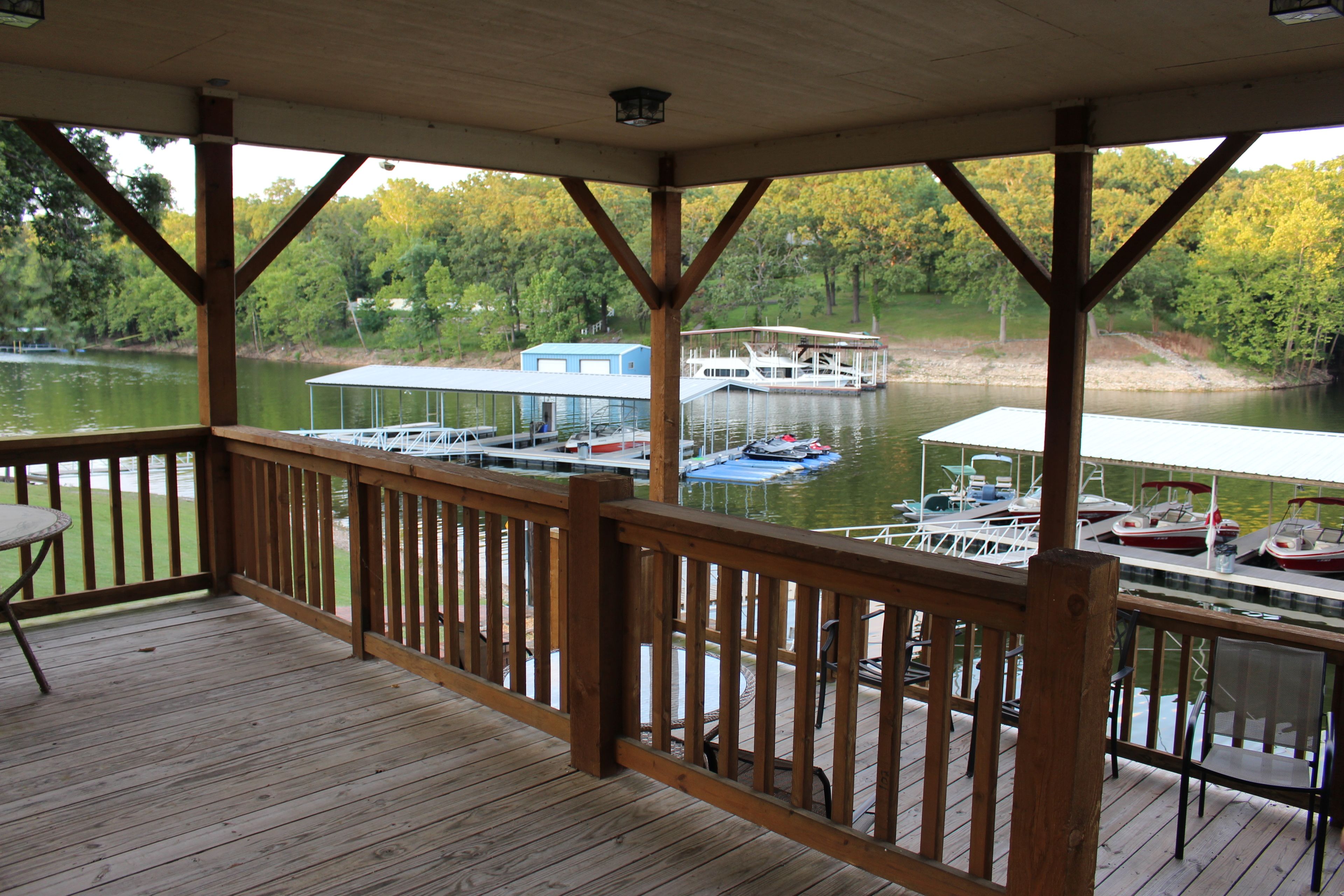 A wooden deck with a view of a dock and boats on a lake.