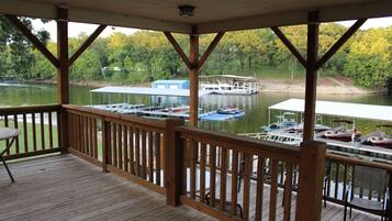 A wooden deck with a view of a dock and boats on a lake.
