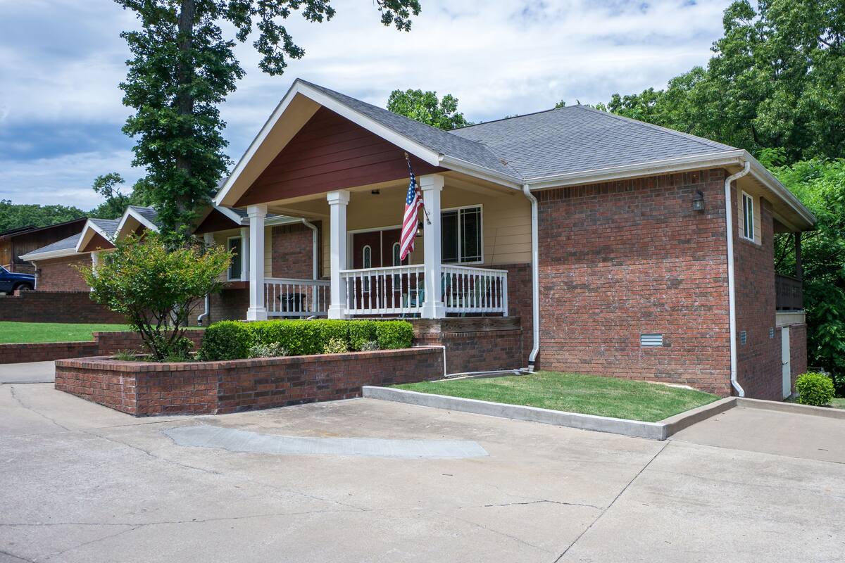A brick building with a porch and a flag.