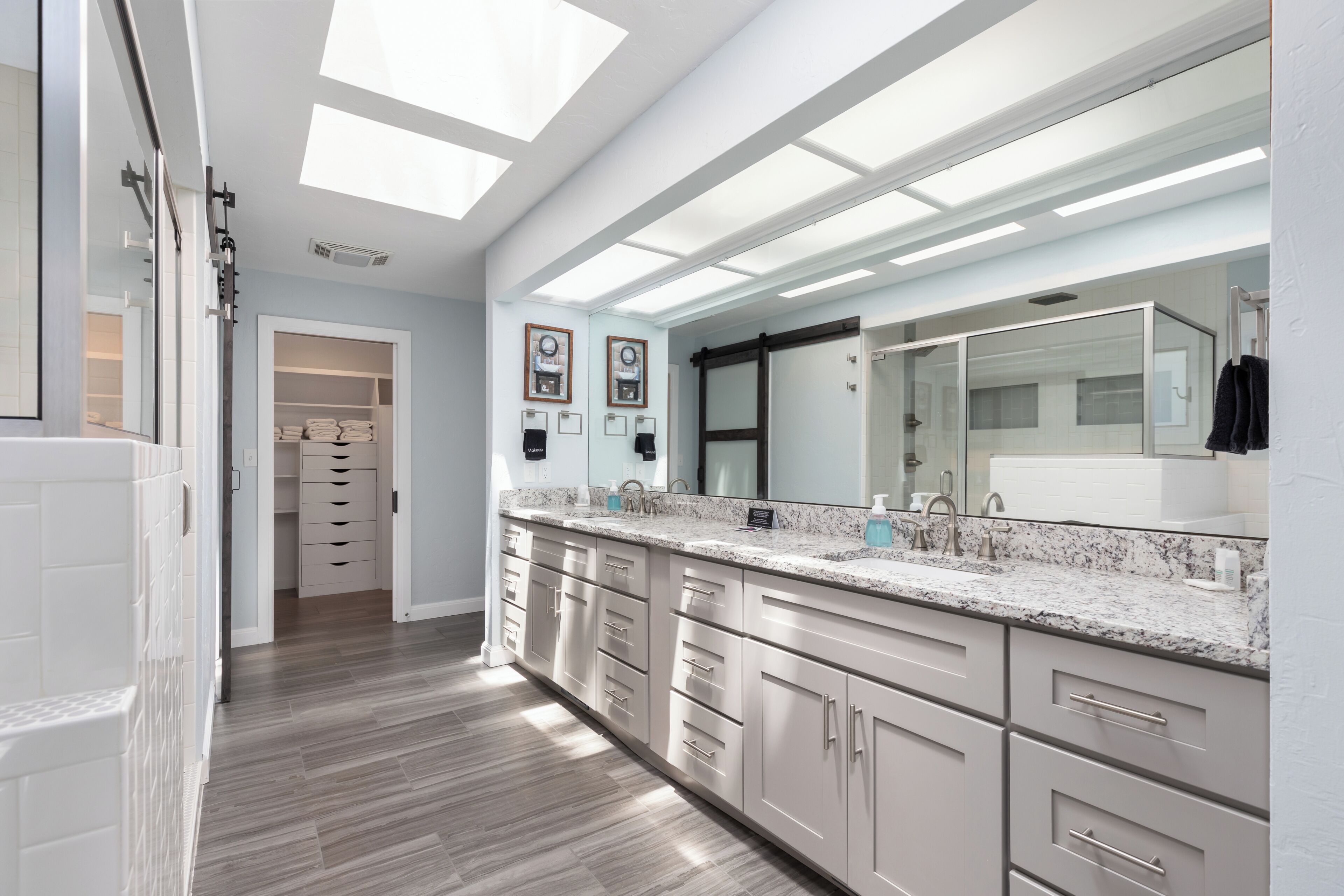 A modern bathroom with a skylight, a large mirror, and a walk-in closet.