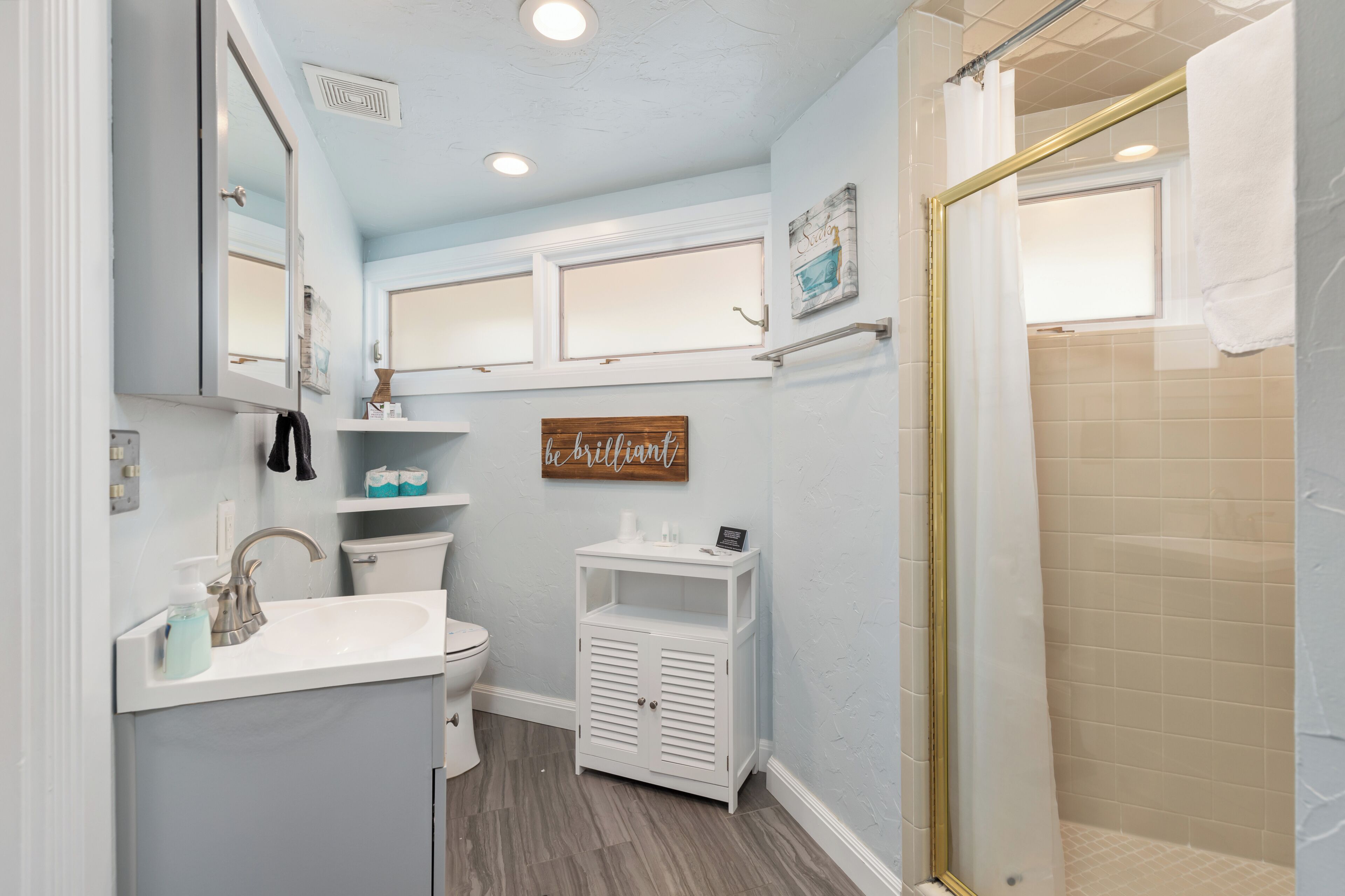 A bathroom with a sink, toilet, and shower area.