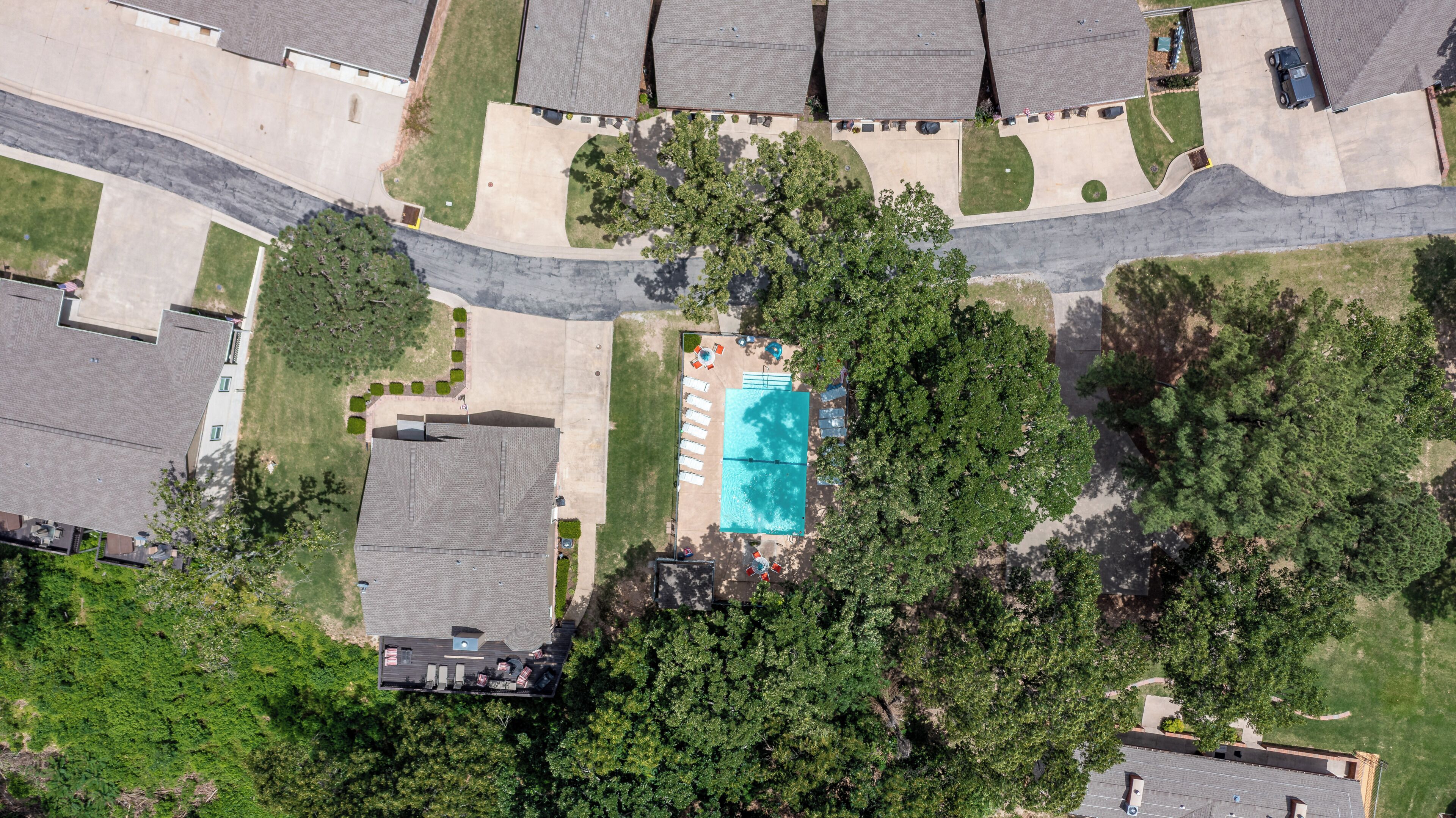 Vista aérea de una zona residencial con piscina, varias casas y un camino de entrada.