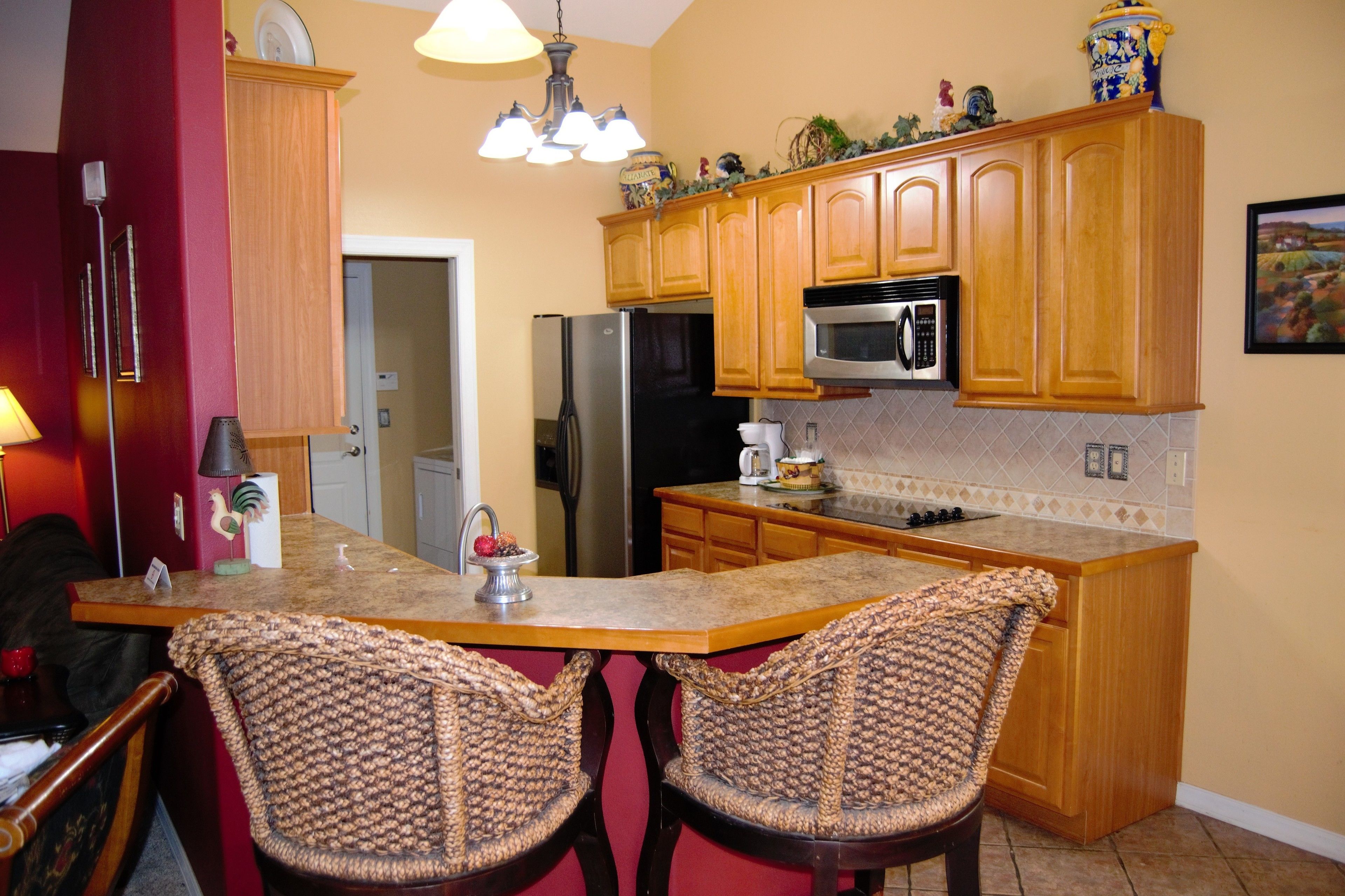 A kitchen with wooden cabinets, a stainless steel refrigerator, a microwave, and a granite countertop.