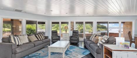 A spacious living room with a grey sofa, a white coffee table, and a blue rug.
