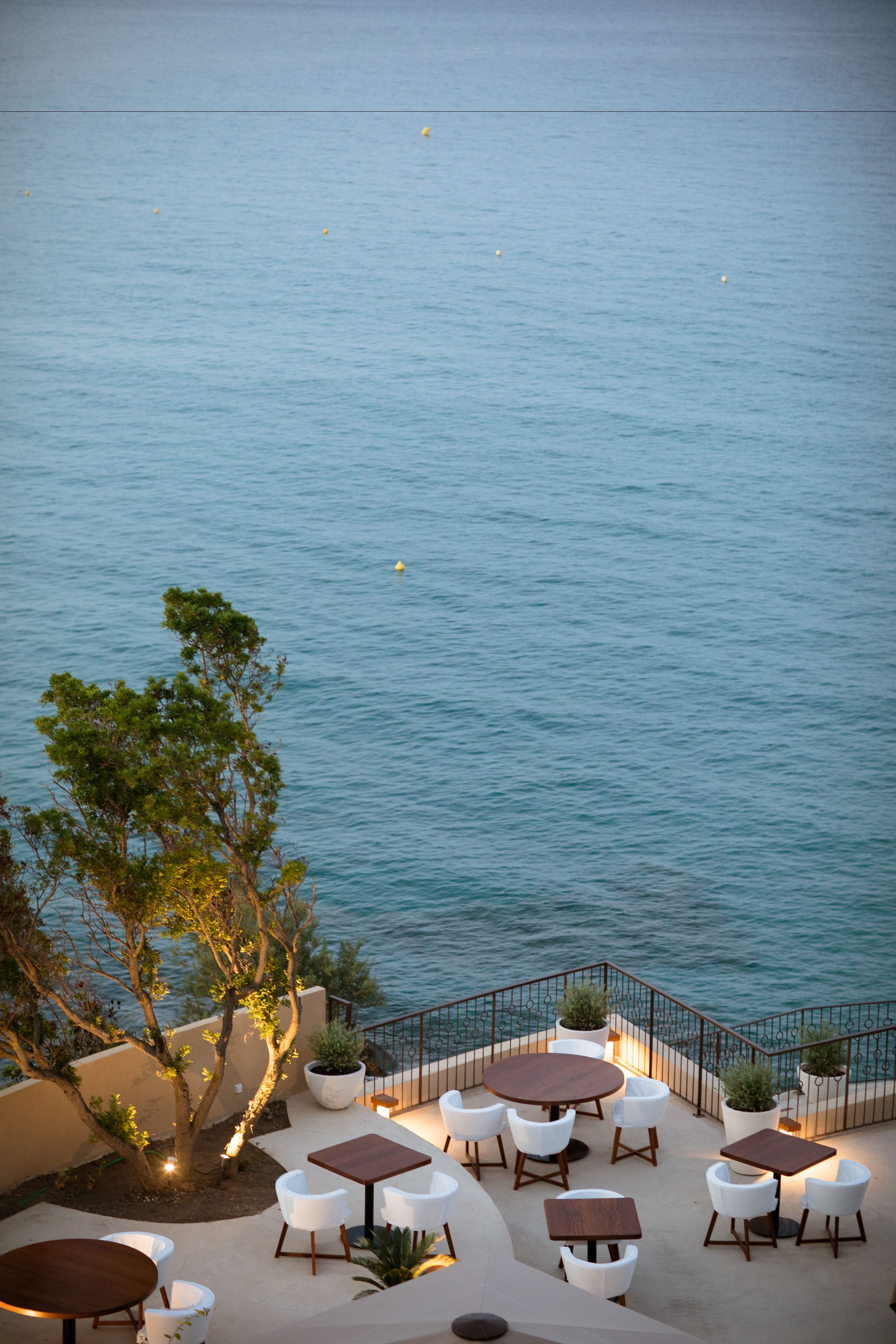 An outdoor seating area with tables and chairs, overlooking a body of water.