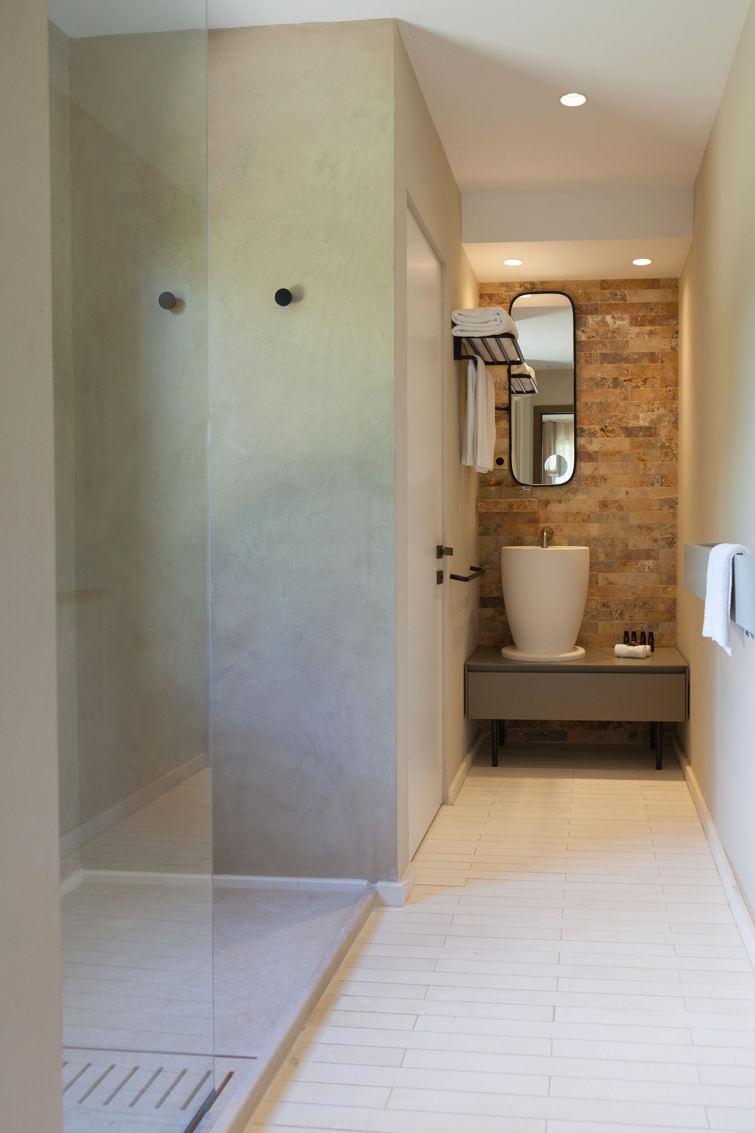 A modern bathroom with a glass-enclosed shower, a large sink, and a mirror above it.