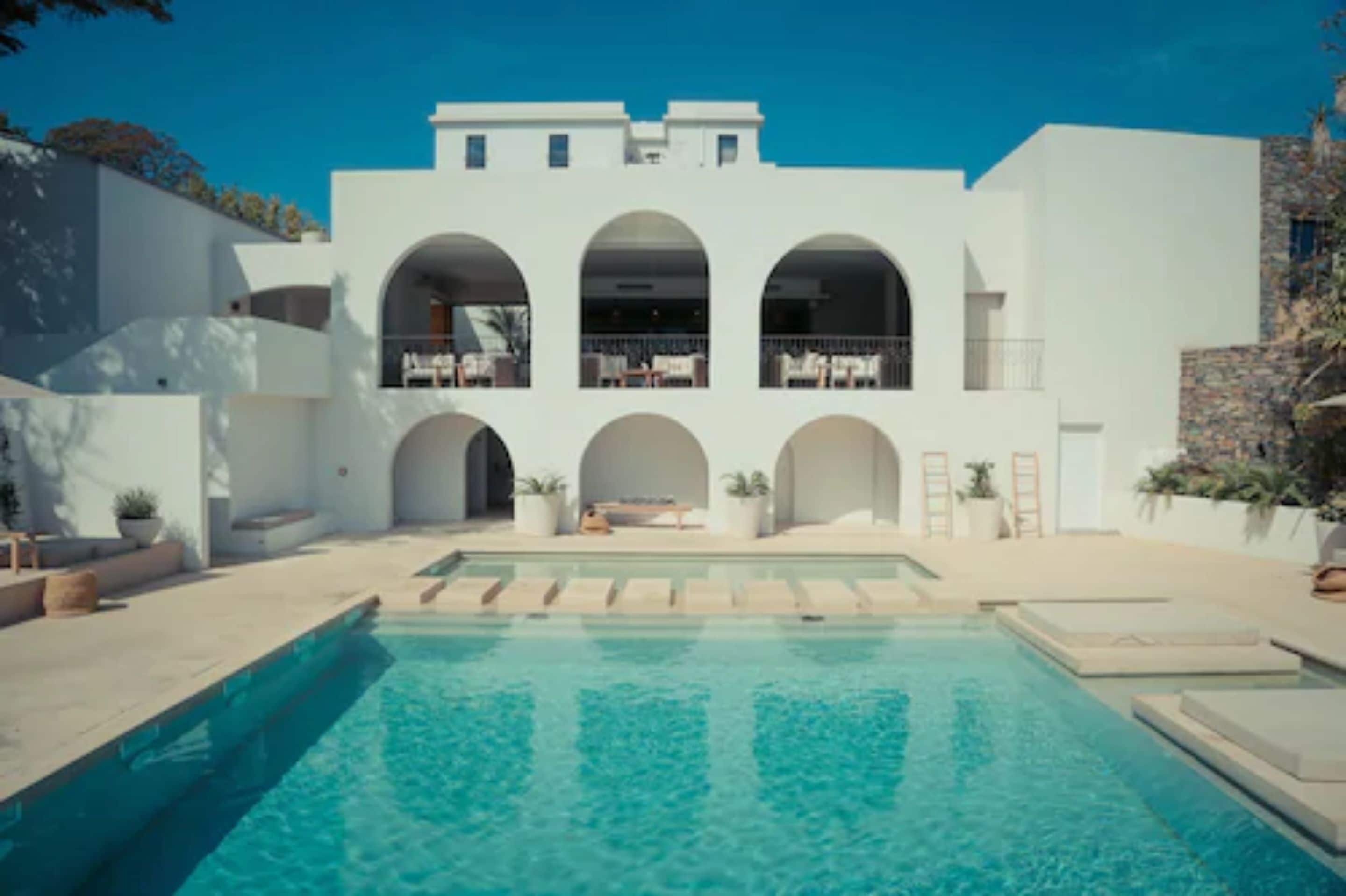 Un edificio moderno con piscina, con ventanas arqueadas y techo plano.