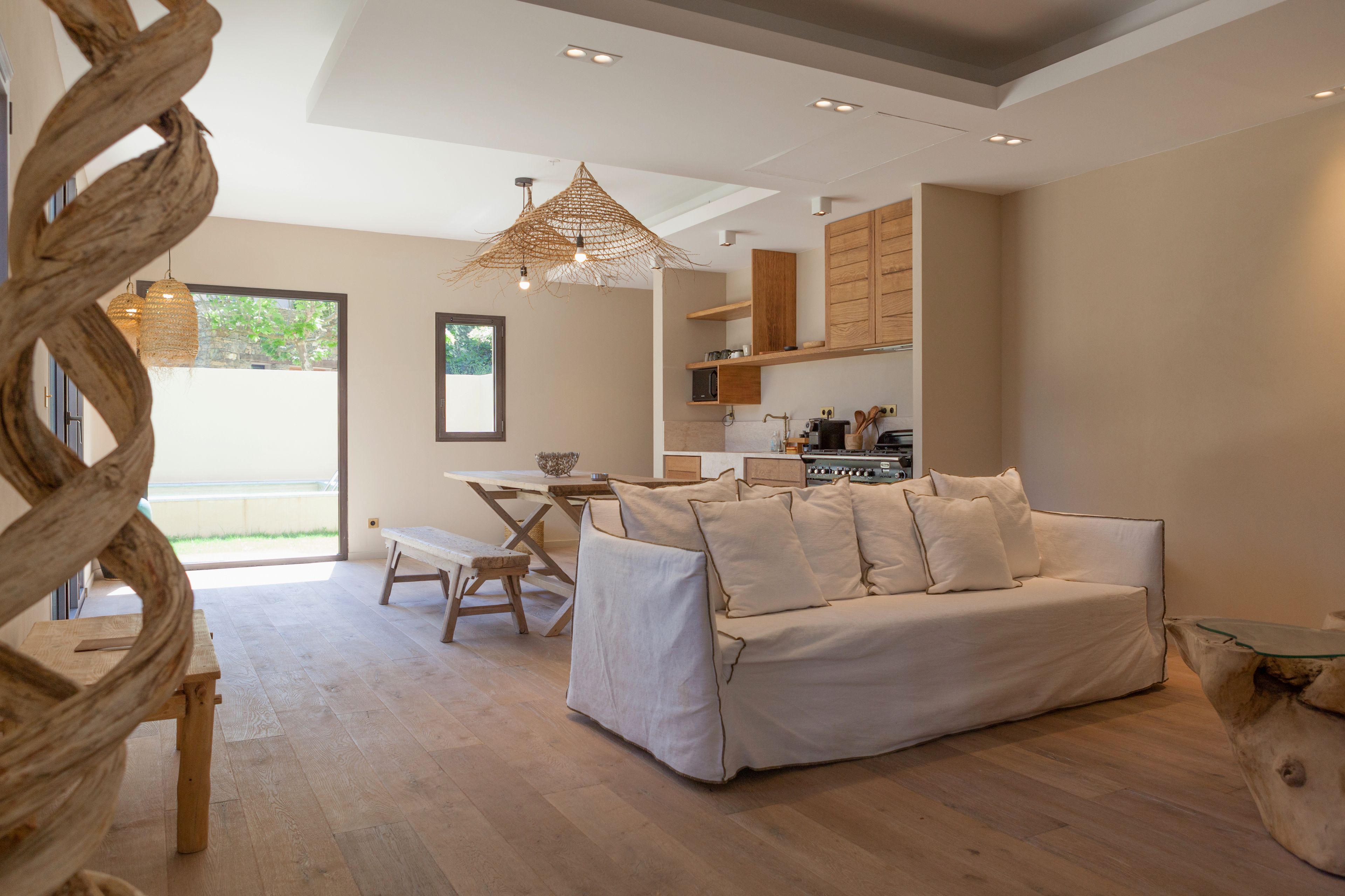 Una sala de estar moderna con sofá, mesa de comedor de madera y una cocina al fondo.