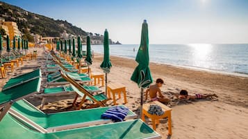 Een privéstrand, ligstoelen aan het strand, parasols, strandlakens