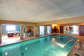 Ein Hallenbad mit Steinwand, Sitzgelegenheit und Blick ins Freie.
