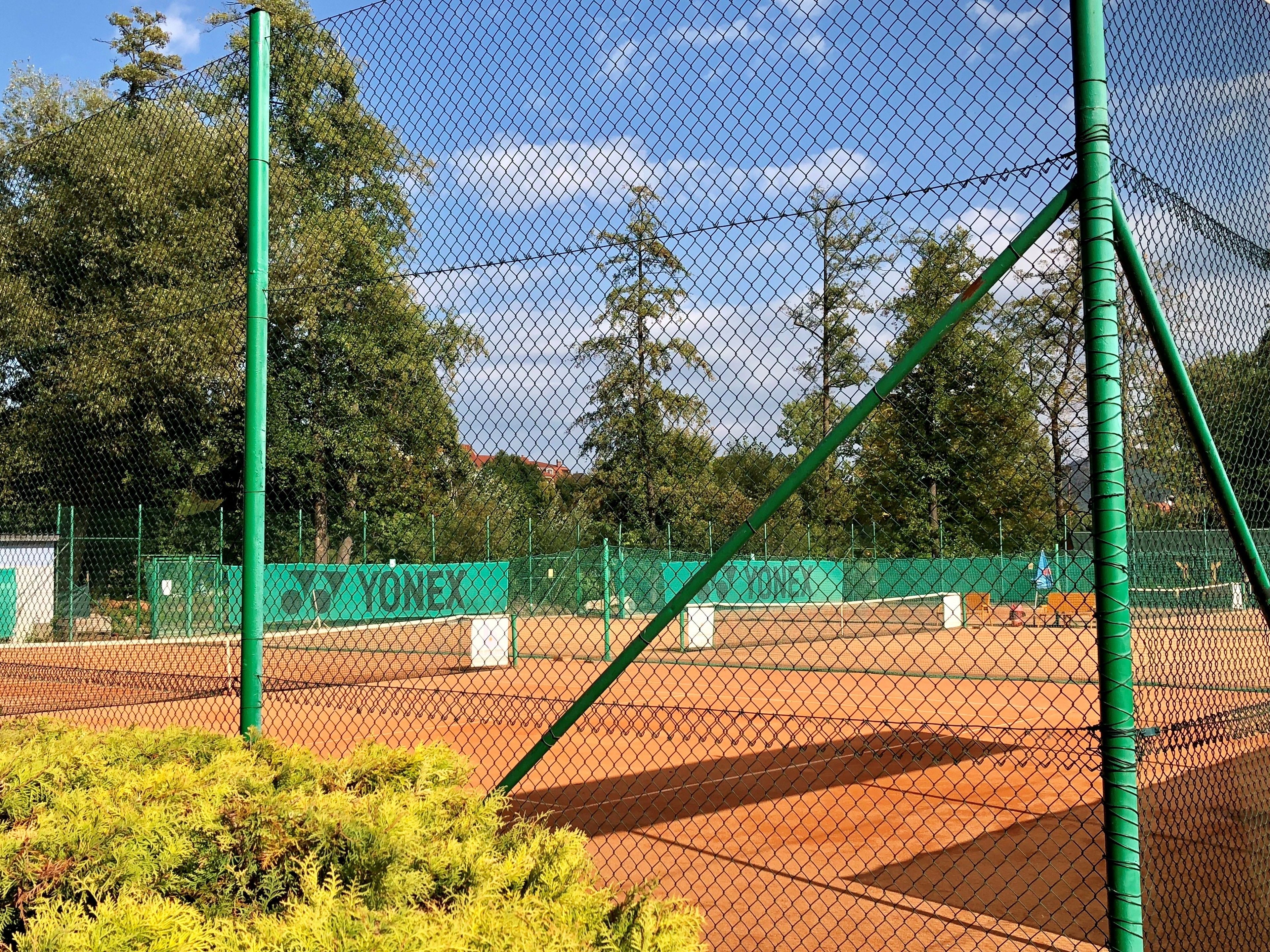 A tennis court with green fencing and a net.