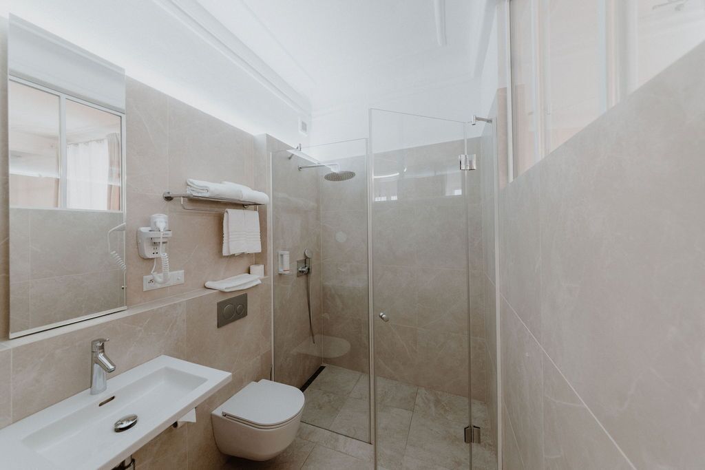 A modern bathroom with a glass-enclosed shower, a white sink, and a toilet.