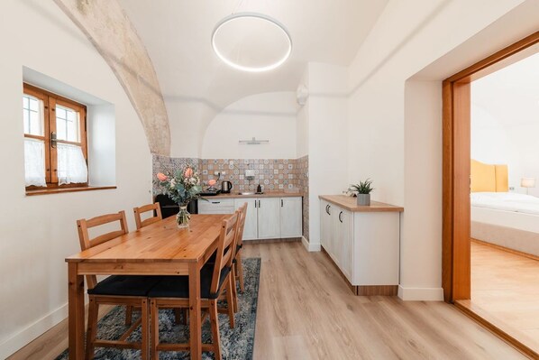 A modern kitchen with white cabinets, a wooden dining table, and a small countertop. - Penzion Austis (Znojmo)