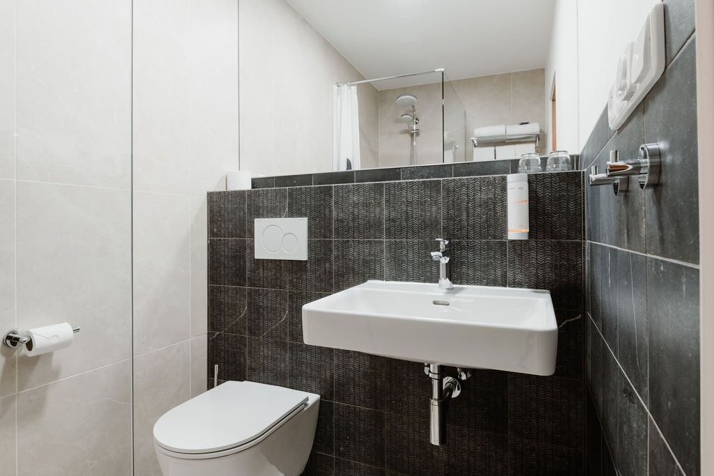 A modern bathroom with a toilet, a sink, and a shower.