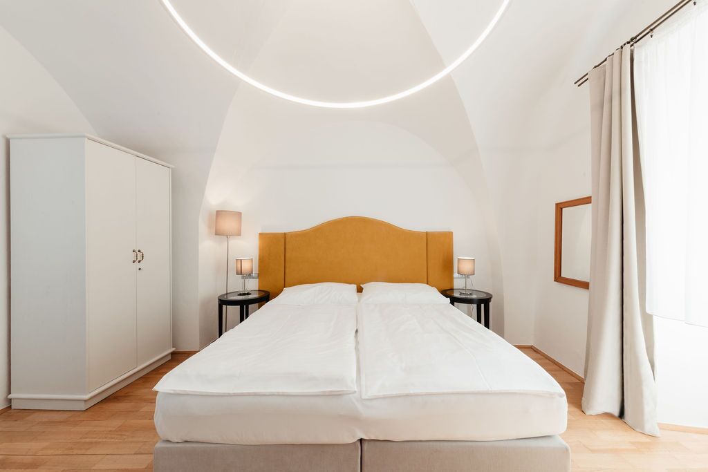 A bedroom with a bed, two bedside tables, a wardrobe, and a ceiling light fixture.