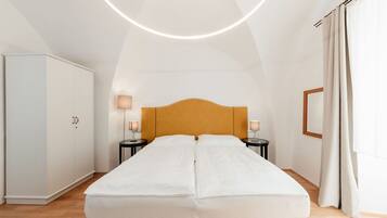 A bedroom with a bed, two bedside tables, a wardrobe, and a ceiling light fixture.