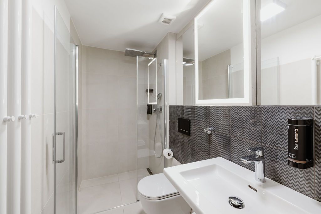 A modern bathroom with a glass-enclosed shower, a white sink, and a mirror.
