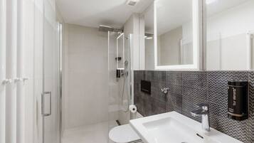 A modern bathroom with a glass-enclosed shower, a white sink, and a mirror.