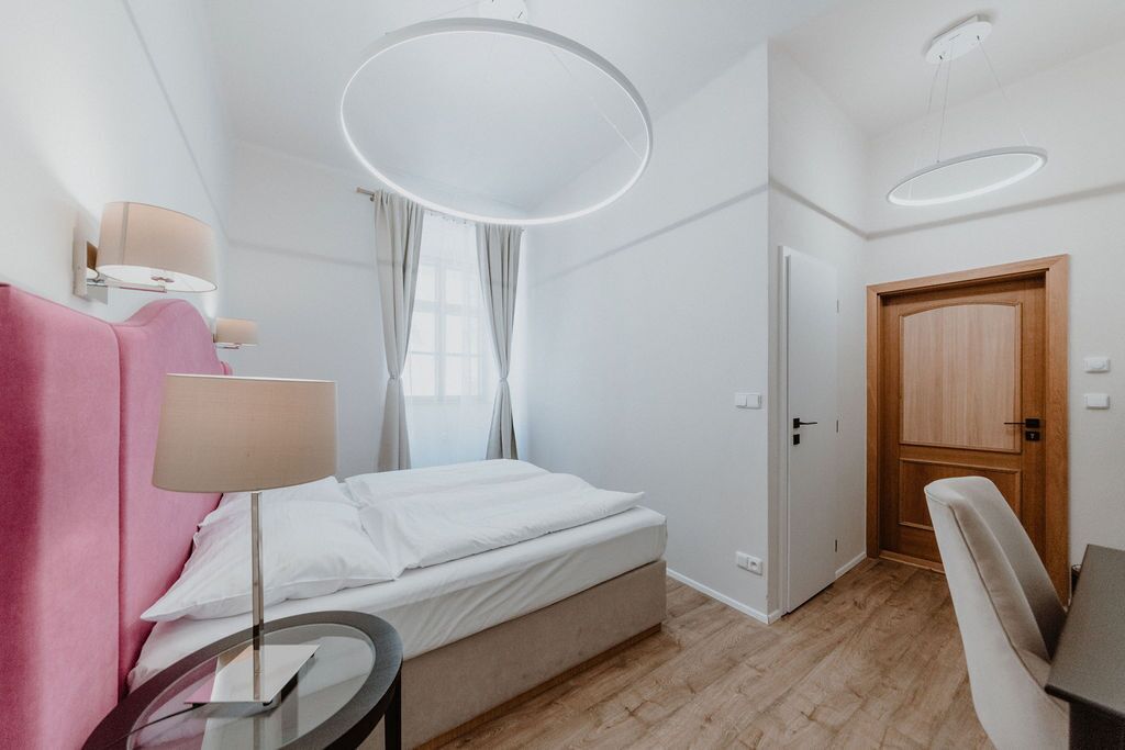Un dormitorio moderno con cama, mesita de noche, lámpara y una luz de techo circular.