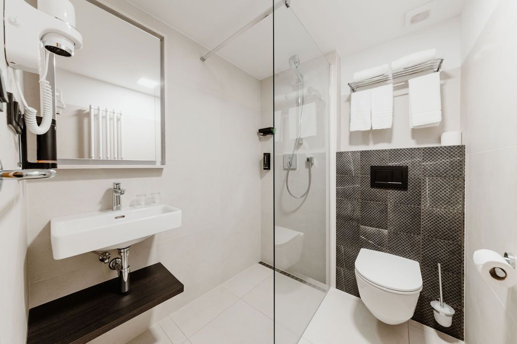 A modern bathroom with a glass-enclosed shower, a white sink, and a toilet.