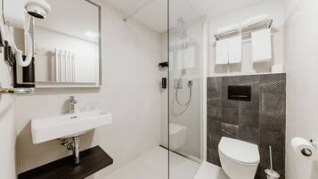 A modern bathroom with a glass-enclosed shower, a white sink, and a toilet.